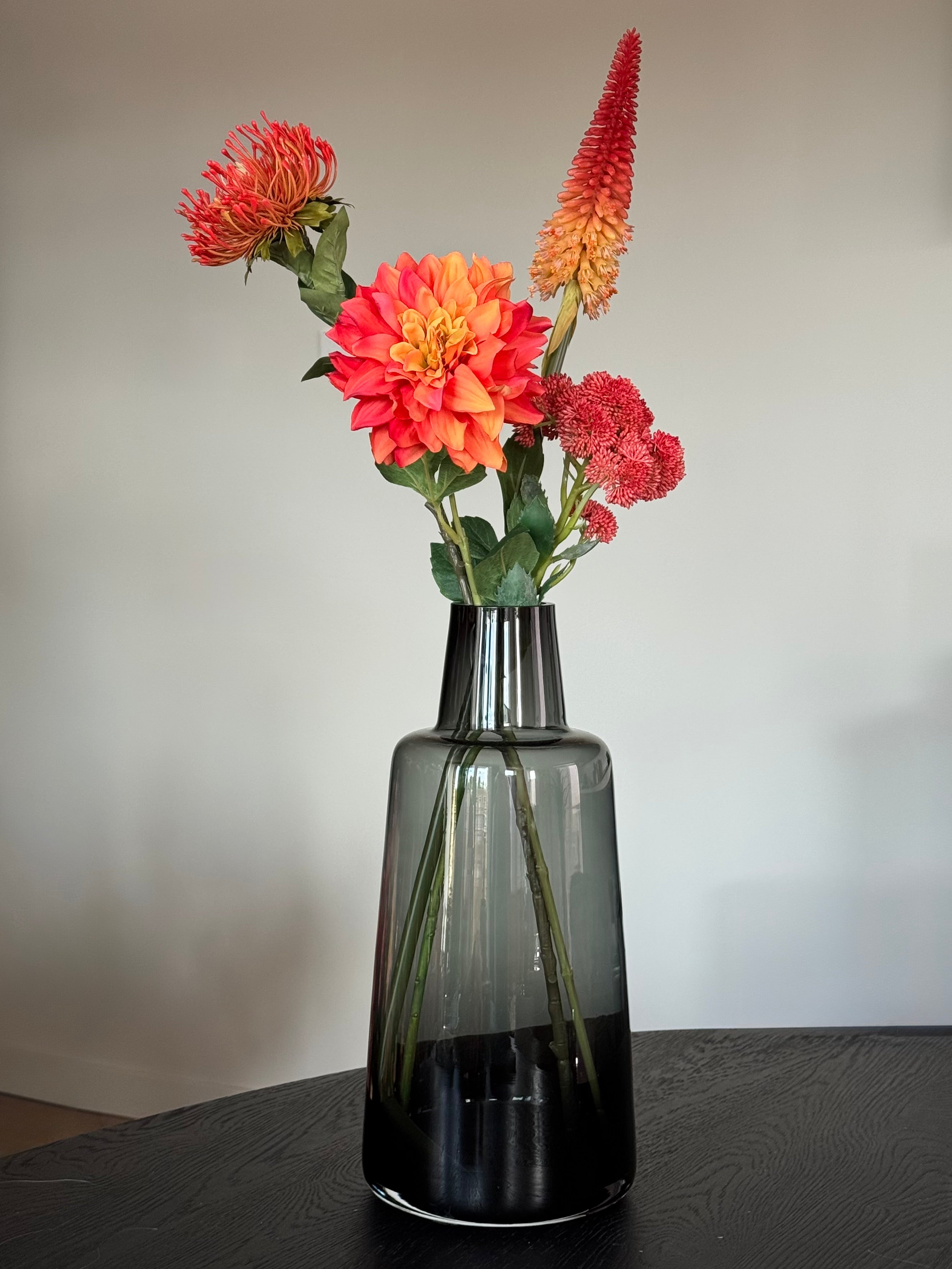 Design kunstboeket in rood met zwart doorschijnende vaas