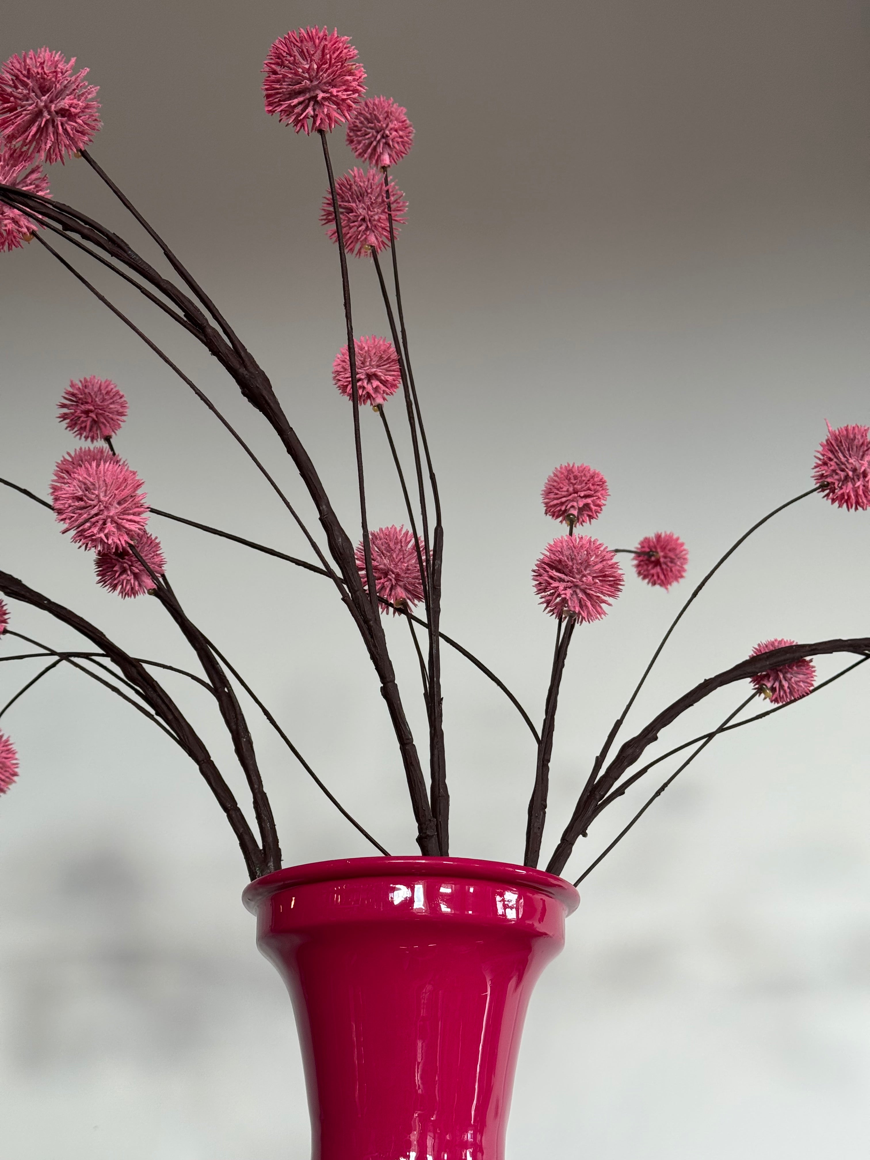 knal roze vaas met kunsttakken met roze bolletjes close up