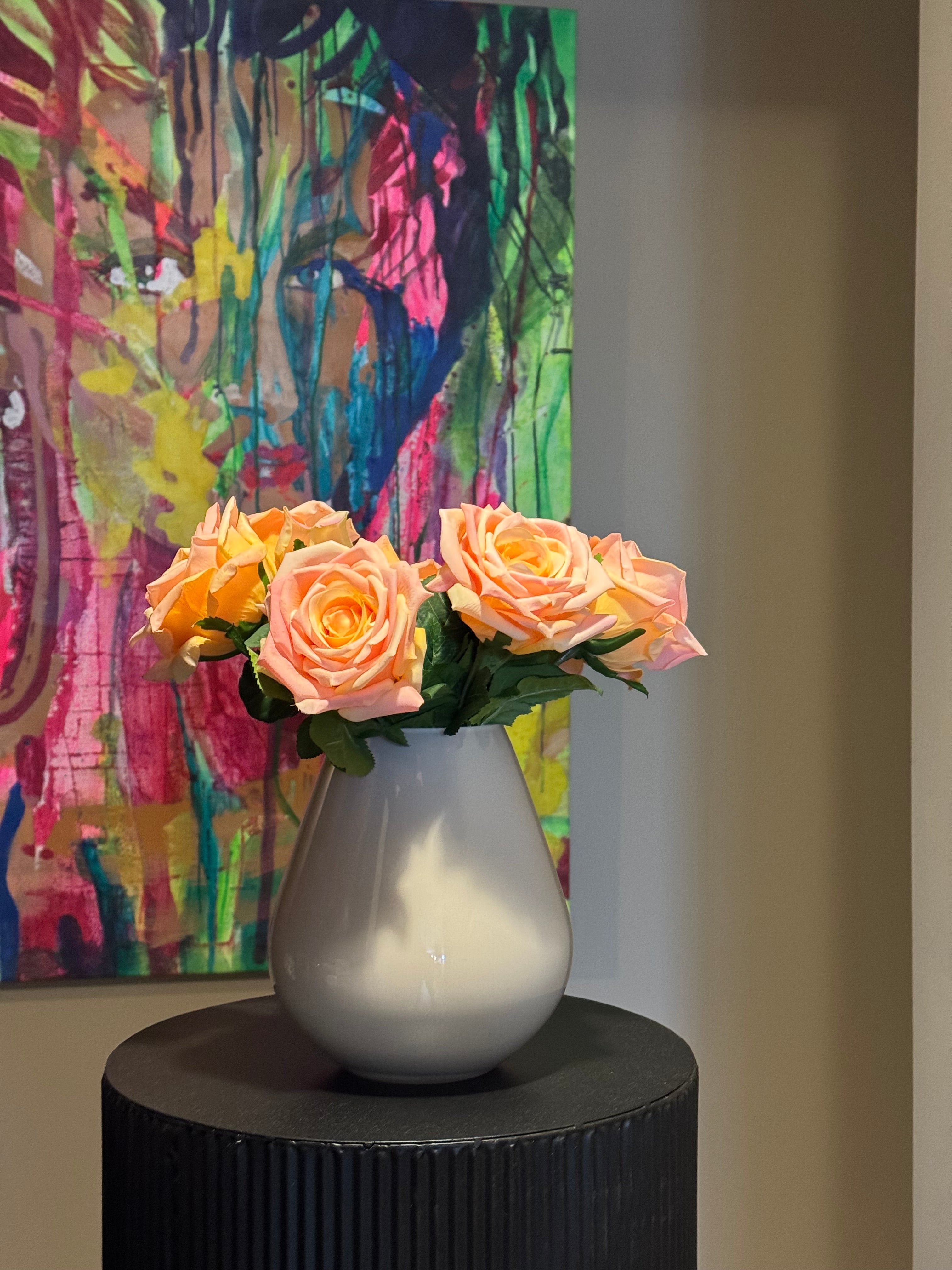 kunstboeket real toch rozen in artistiek interieur met kleurrijk schilderij op de achtergrond