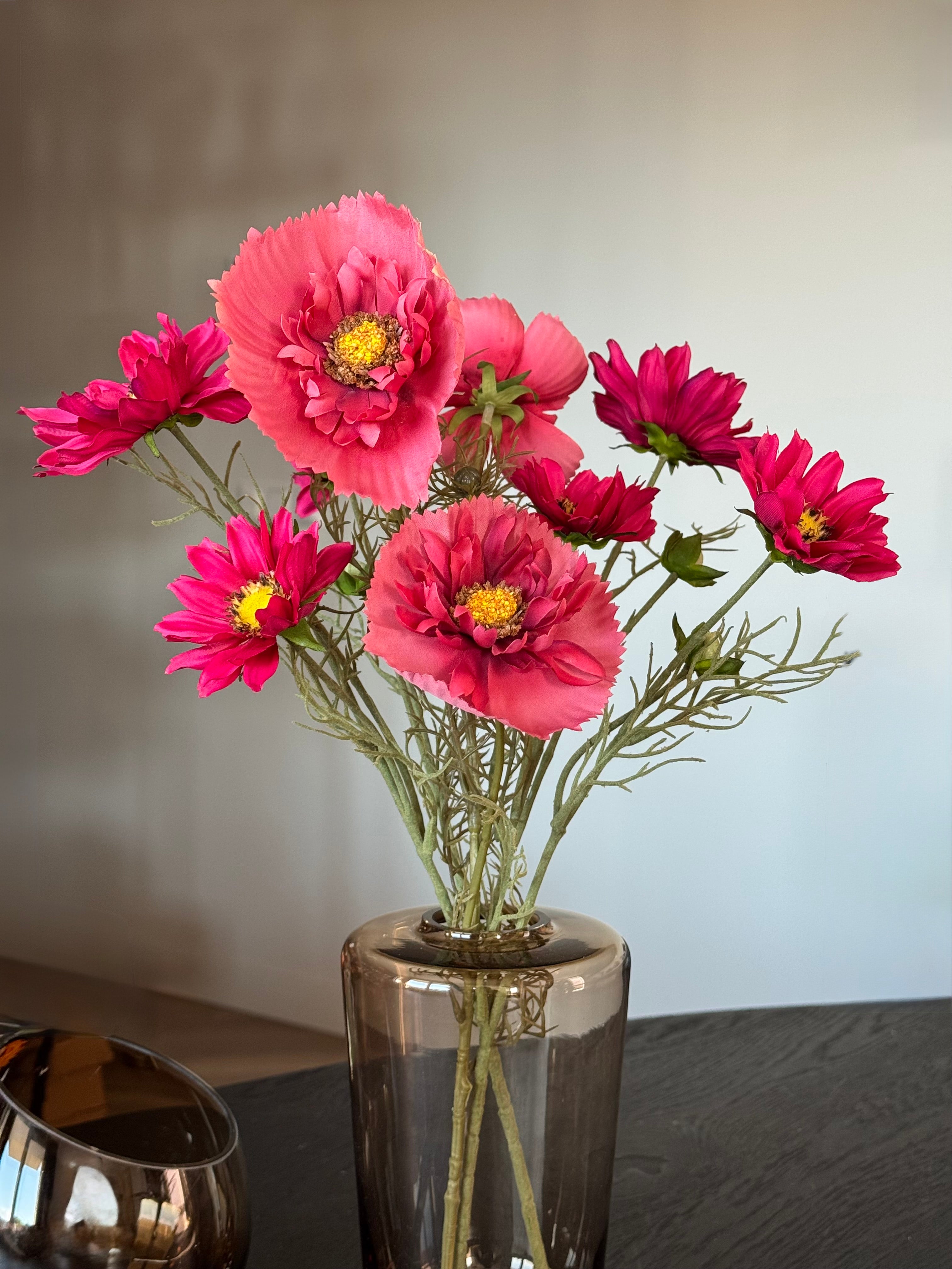 roze kunstbloemen die net echt lijken in een bruine vaas met windlicht