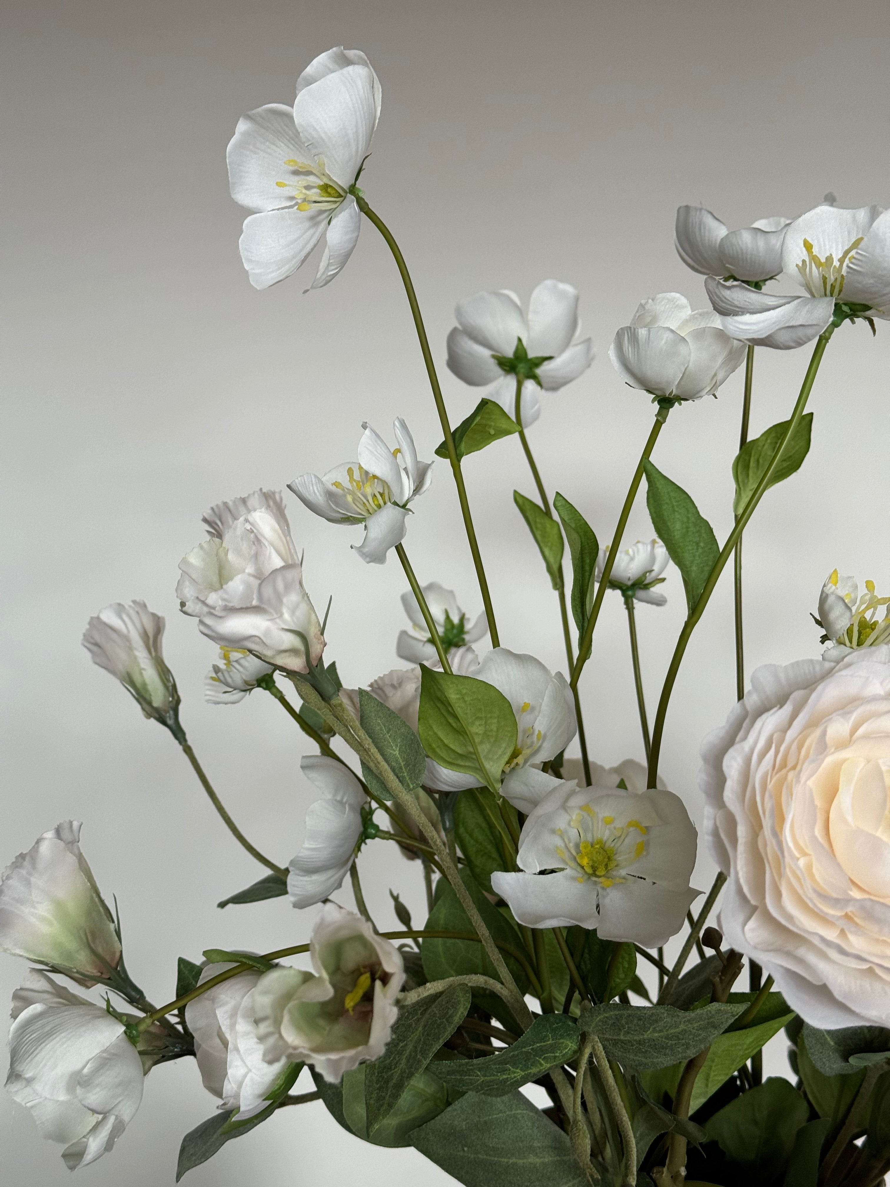 Detail van witte zijden bloemen in een stijlvolle beige vaas.