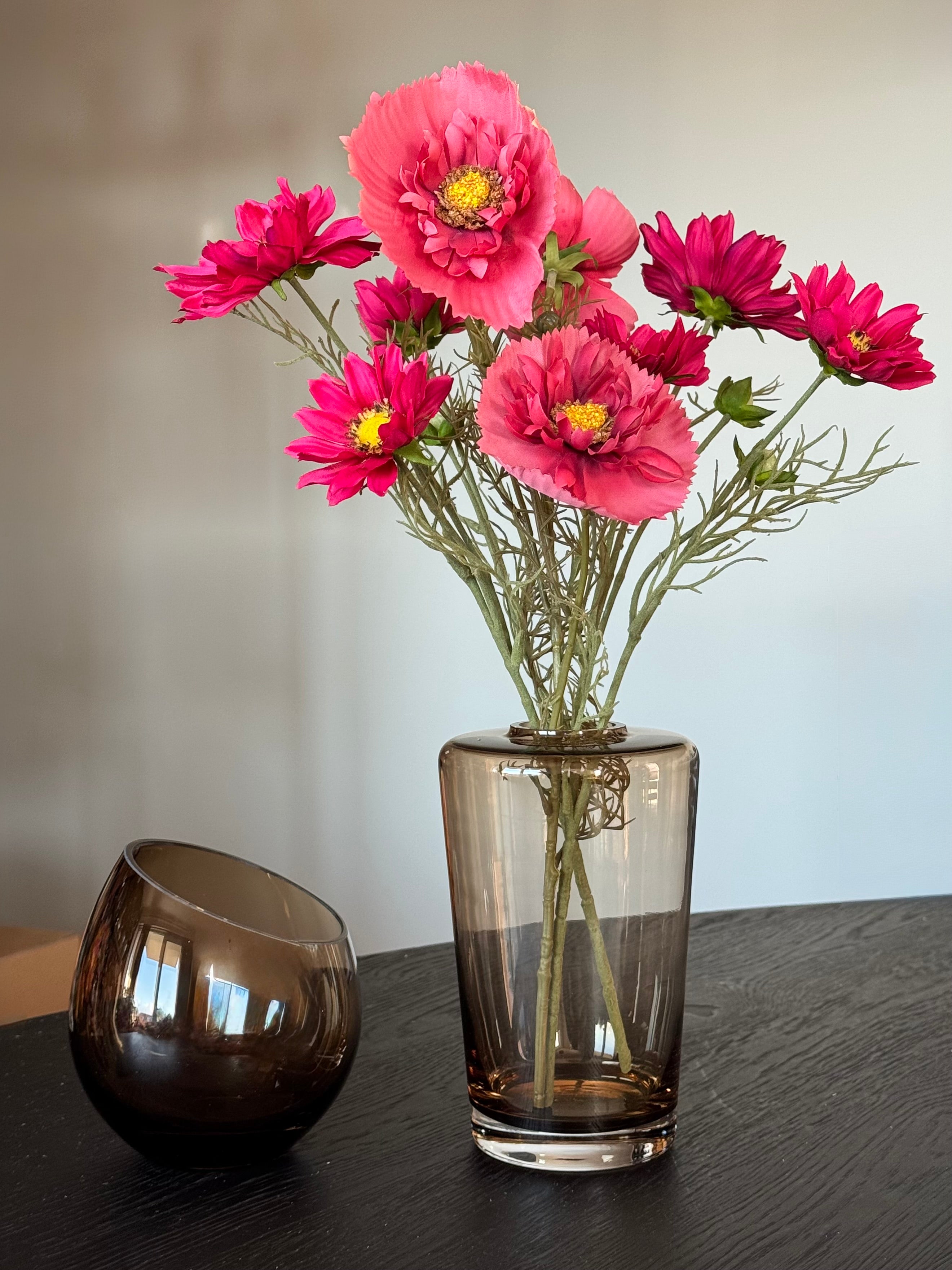 roze kunstbloemen die net echt lijken in een bruine vaas met windlicht