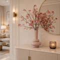 Oranje zijden bessentakken van Silk Ka in beige vaas op een dressoir in een lichtgekleurd hotel chique interieur