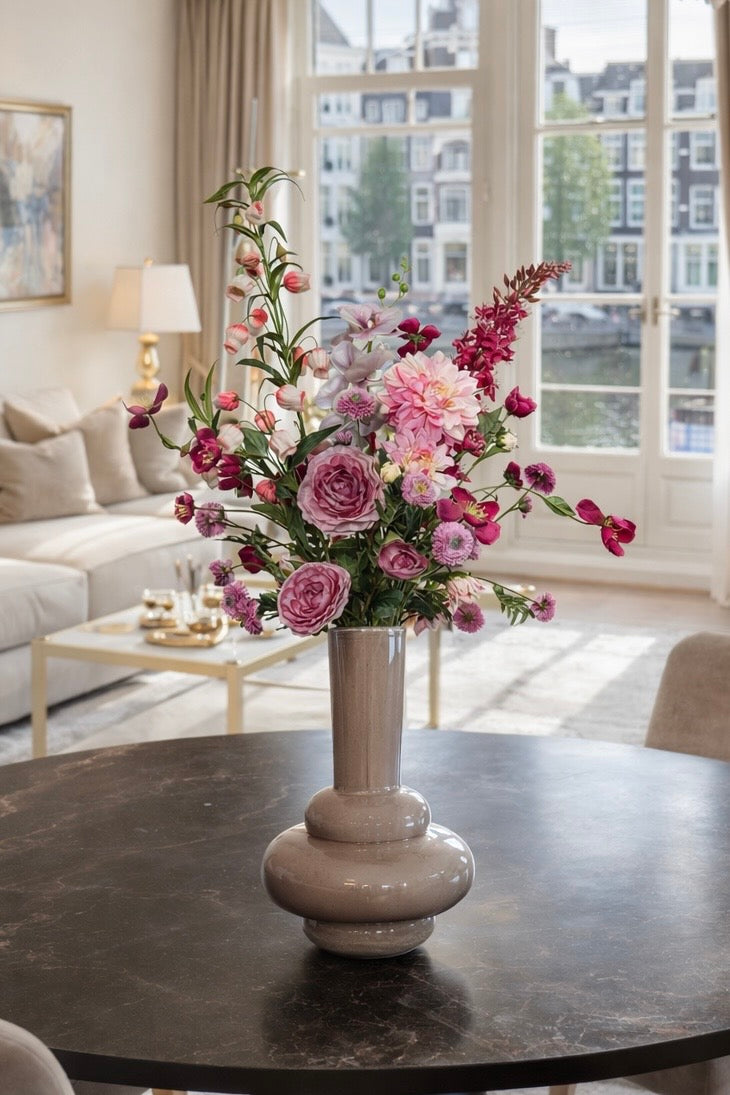 Elegant roze zijden boeket als blikvanger op een eettafel in een luxe appartement.