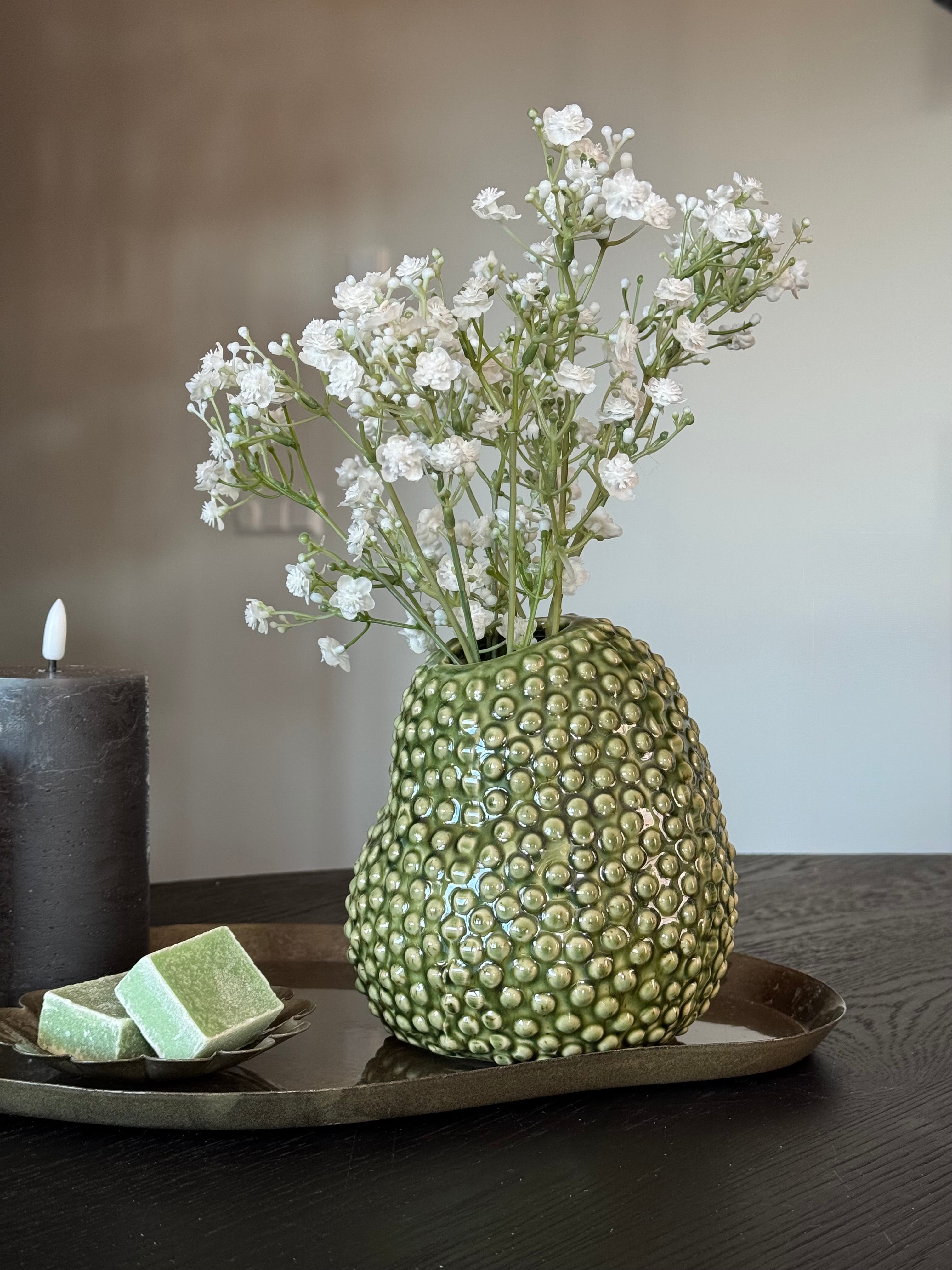 Close up van de groene tafelset met augurk vaas, gipskruid, amberblokjes en led kaarsen. 